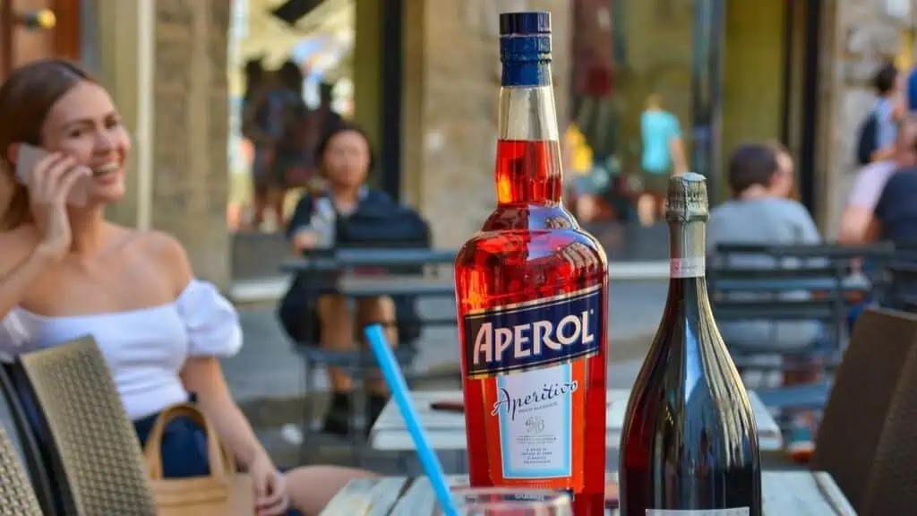 Fles Aperol en prosecco voor Aperol Spritz maken op terras met zomerse sfeer