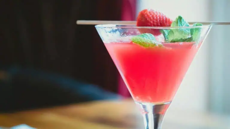 Roze cocktail met aardbei en munt geserveerd in een martiniglas